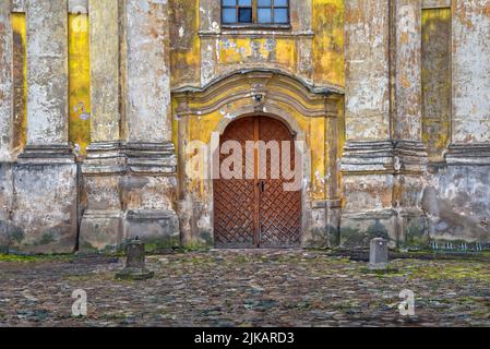 Ancient entrance to the historical building old city of Vilnius. Heavy brown wooden door and old rough stone wall Stock Photo