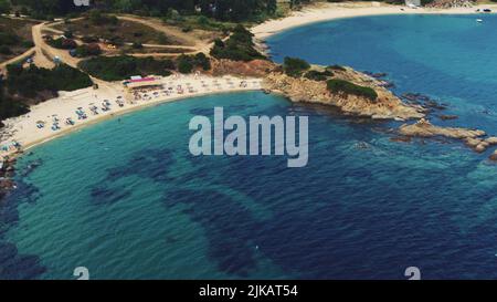 Some tourists relaxing on quiet sandy beach of Sarti. Greek summer holidays. Aerial view. Shallow turquoise sea water. High quality photo Stock Photo