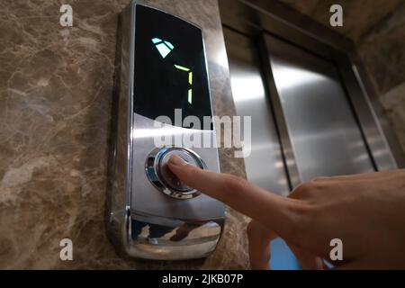 Close-up of a finger pressing the elevator call button. Selective focus Stock Photo
