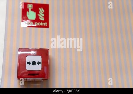 Close-up of a red fire alert button on a striped wall. Selective focus Stock Photo