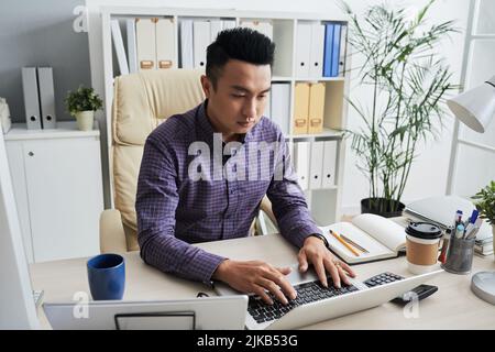 Asian young businessman working on laptop in his office Stock Photo