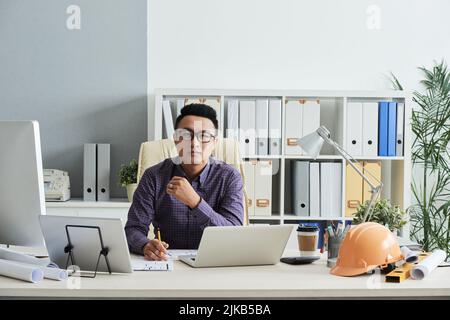 Portrait of smiling young engineer working in his bureau Stock Photo
