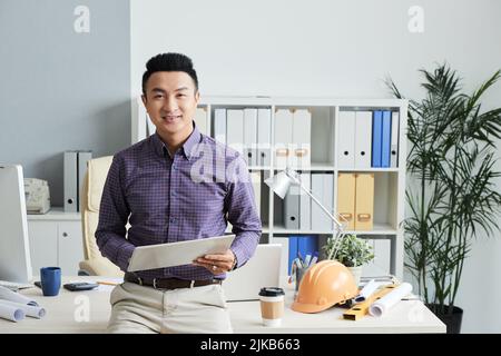 Portrait of smiling Asian engineer with digital tablet smiling and looking at camera Stock Photo