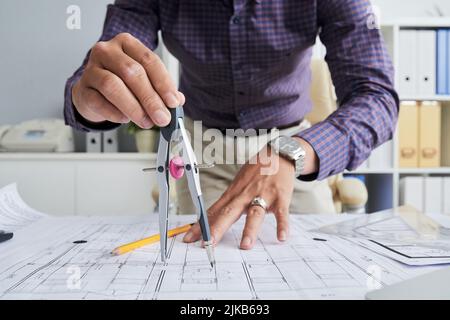 Close-up image of architect using compasses when drawing blueprint Stock Photo