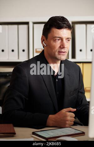 Serious businessman having distant meeting with colleagues and discussing important issues Stock Photo