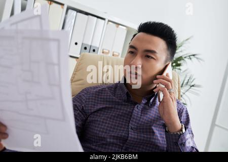 Vietnamese architect consulting client on the phone Stock Photo
