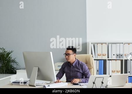 Vietnamese engineer working on computer in his office Stock Photo