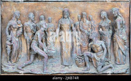 MONOPOLI, ITALY - MARCH 6, 2022: The bronze relief Miralce The Feeding the multitude on the gate of church Chiesa di Sacro Cuore by Wolfgang Stempfele Stock Photo