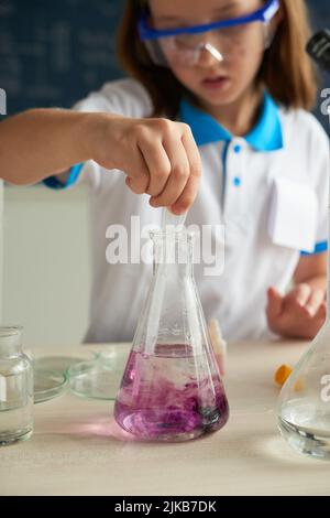 School girl mixing water with purpple substance in it Stock Photo