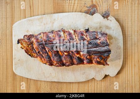 Grilled barbecue pork ribs, on wooden serving board, on wooden table background. Top view. Stock Photo
