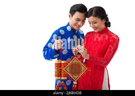 Cheerful young Asian couple taking selfie in traditional dresses at Chinese New Year celebration, decorations with best wishes inscription Stock Photo