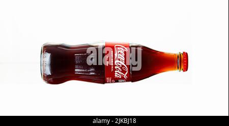 Chisinau, Moldova - July 31, 2022: Glass bottle of Coca Cola drink on white background. The drink is produced and manufactured by The Coca-Cola Compan Stock Photo