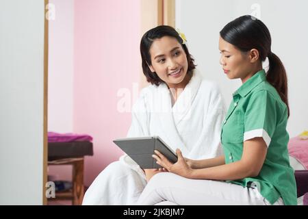 Beautician consulting pretty female client in spa salon Stock Photo