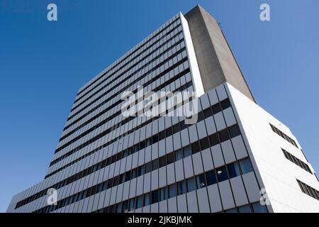 Exterior of a modern office building made of glass and plastic and concrete panels in several layers against a blue cloudless sky. Real estate Stock Photo