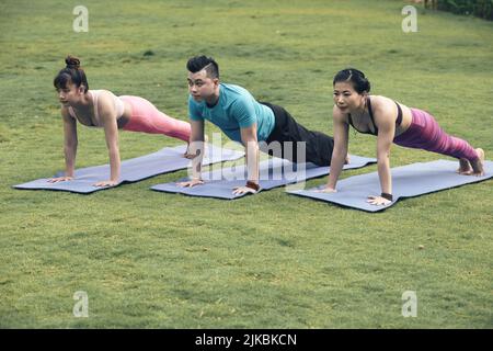 Young Asian people doing plank exercise outdoors Stock Photo