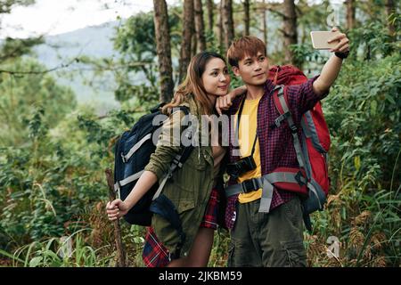 Young couple taking photos in forest together Stock Photo