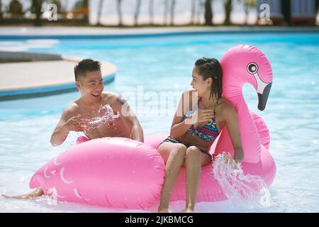 Young Vietnamese couple having fun in swimming pool Stock Photo