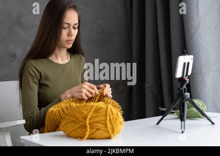young woman blogger writes video knitting, girl learns to knit by attending online class, blog and hobby Stock Photo