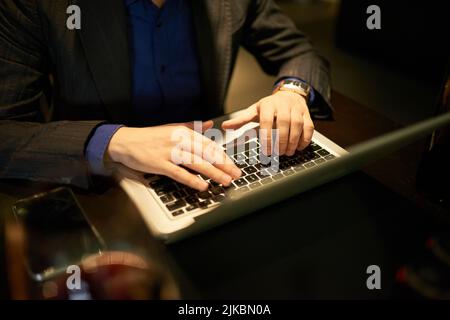 Hands of businessman working on laptop at restaurant table Stock Photo