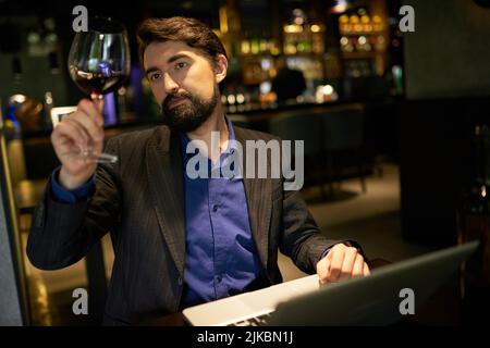 Somelier looking at glass of red wine to check the color Stock Photo
