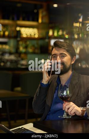 Portrait of handsome man drinking wine and calling on the phone Stock Photo