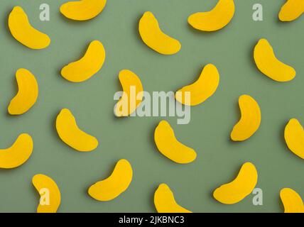 Jelly candies in shape of bananas as pattern on green background Stock Photo