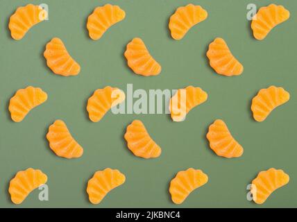 Jelly candies in shape of orange slice as pattern on green background Stock Photo