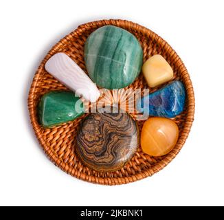 Cacholong, chrysoprase, opal, rose calcite, aventurine, aragonite, stromatolite, apatite and turquoise natural stone on rattan plate isolated on white Stock Photo