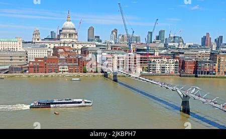 Uber Boat approaches the Millennium bridge, over the Thames, looking over at St Pauls Cathedral and construction cranes, London Stock Photo