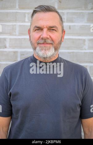 Serious bearded senior man looking thoughtfully at the camera in a cropped close up upper body portrait Stock Photo