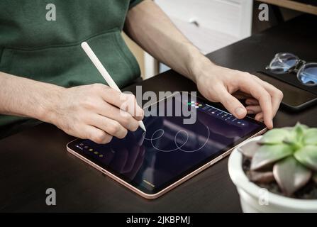 KIEV, UKRAINE - DECEMBER 21, 2021:Man with Apple Pencil using iPad Pro for drawing. iPad Pro was created and developed by the Apple inc. Stock Photo