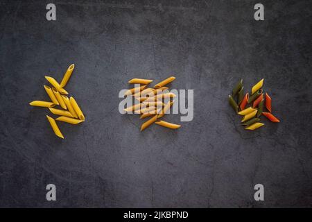 Three types of penne pasta, wholemeal, integrale, tri colore and regular on a background Stock Photo