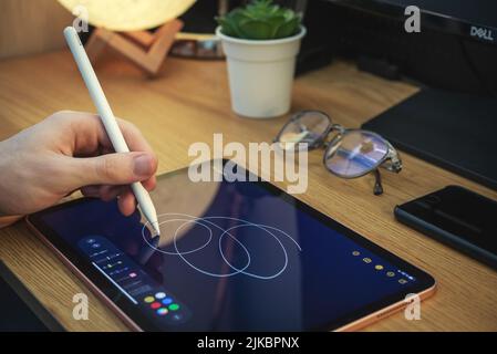 KIEV, UKRAINE - DECEMBER 21, 2021:Man with Apple Pencil using iPad Pro for drawing. iPad Pro was created and developed by the Apple inc. Stock Photo