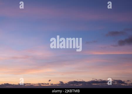 Bright colored sky during dusk hour with golden clouds reflecting the light of the twiligt sun. Background of white space, sky replacement. Stock Photo