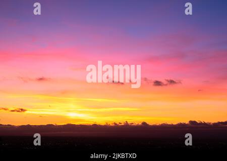 Bright colored sky during dusk hour with golden clouds reflecting the light of the twiligt sun. Background of white space, sky replacement. Stock Photo