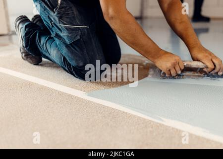 A closeup shot of a worker applying grey epoxy resin on the floor Stock Photo