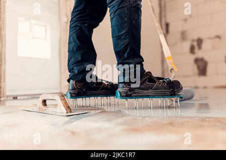 A closeup shot of a worker applying grey epoxy resin on the floor Stock Photo
