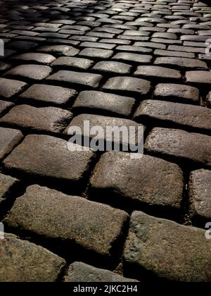 Old road made of laid out stones, in the rays of the sun Stock Photo