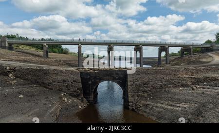 Remnants of an old bridge that’s usual submerged under water is full exposed as water in the reservoir is severally depleted at Baitings Reservoir near Ripponden West Yorkshire, UK on the 01/08/2022 Stock Photo