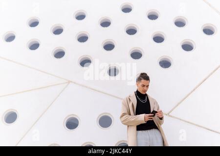 Young hispanic arab man using a smartphone in the street, social media and technology concepts, copy space Stock Photo