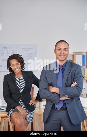 Group portrait of confident young white collar workers looking at camera with wide smiles while having working meeting in open plan office Stock Photo