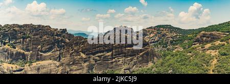 Wide panoramic shot of Meteora rock formations seen from aerial drone view. Beautiful weather, fluffy clouds, blue sky. High quality photo Stock Photo
