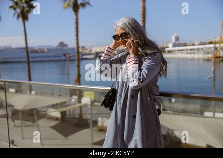 Stylish mature woman using phone at modern city Stock Photo