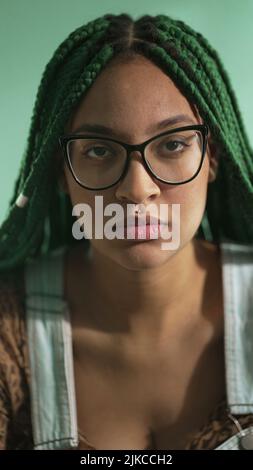 A happy black latin girl with green Box Braids hairstyle smiling