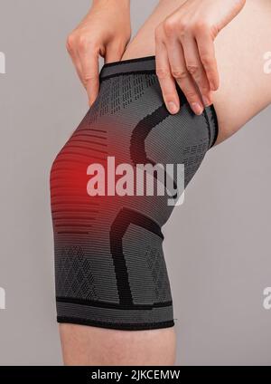 Woman wearing knee brace to reduce pain. Female leg with red spot. Sprain, strain, torn ligaments, kneecap dislocation. Health problems concept. High quality photo Stock Photo
