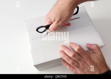close-up of person opening parcel using scissors Stock Photo
