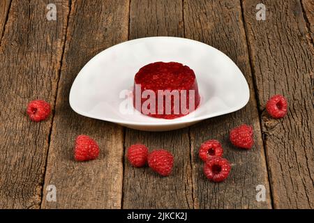 Frozen raspberry smoothies and fresh raspberries on white plate on wooden background. Side view. High resolution photo. Full depth of field. Stock Photo