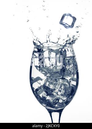 Glass of clear drink or water with ice cube splash. Isolated on white background Stock Photo