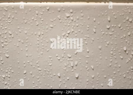 Small water droplets running down wet beige ceramic bathroom tiles Stock Photo
