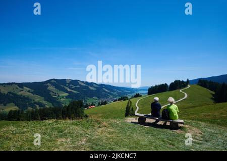 Elderly couple sitting on a bench enjoying the view over the valley Stock Photo